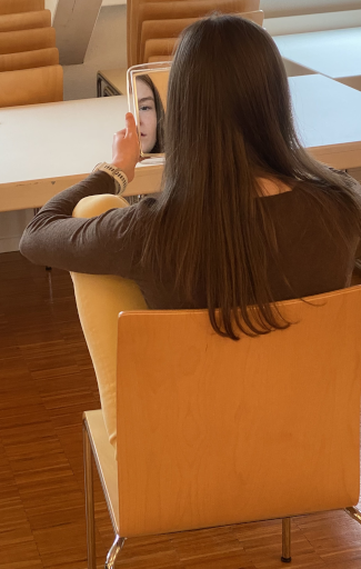 Junge Teilnehmerin blickt in den Spiegel. Ihr Gesicht ist im Spiegel zur Hälfte zu sehen.