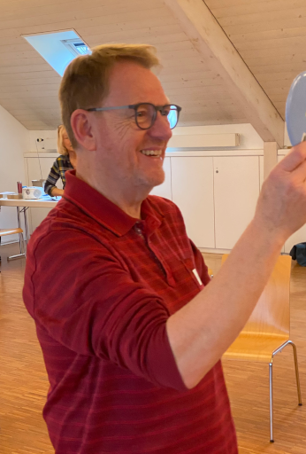 Hans-Ruedi steht mit Blick in den Spiegel und lacht